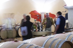 A barrel aging cellar with people tasting wines