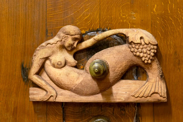 A mermaid carving on a wooden vat