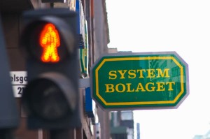 A neon sign for Systembolaget the Swedish monopoly and a pedestrian crossing light