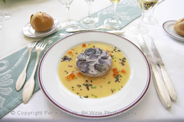 Round timbal with pikeperch fish covered with "scales" of blue coloured potatoes in thin slices served with a beurre blanc butter sauce