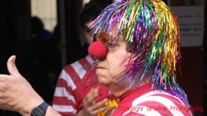 A clown with a red nose giving the thumbs up