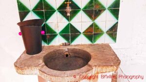 An old and rugged washbasin / sink in stone with tiles